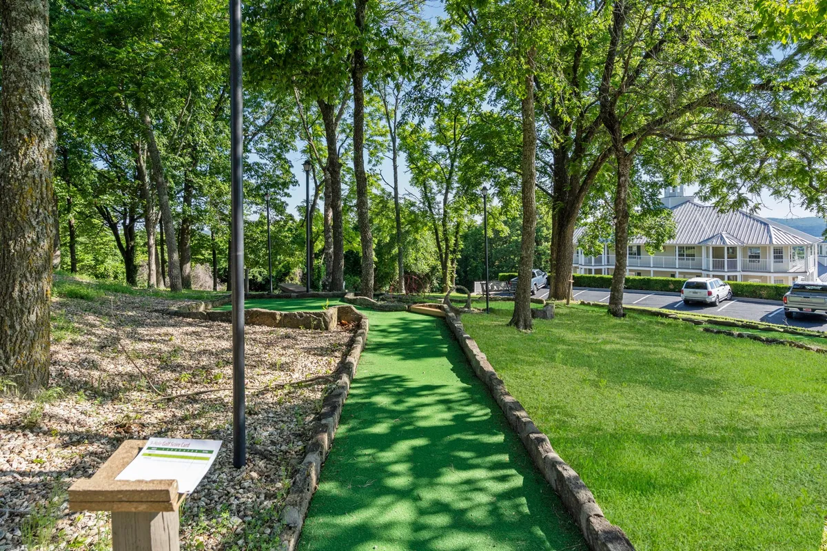 A playful mini-golf pathway winds through lush greenery with a scenic clubhouse in the background, inviting guests to engage in friendly games and outdoor fun.
