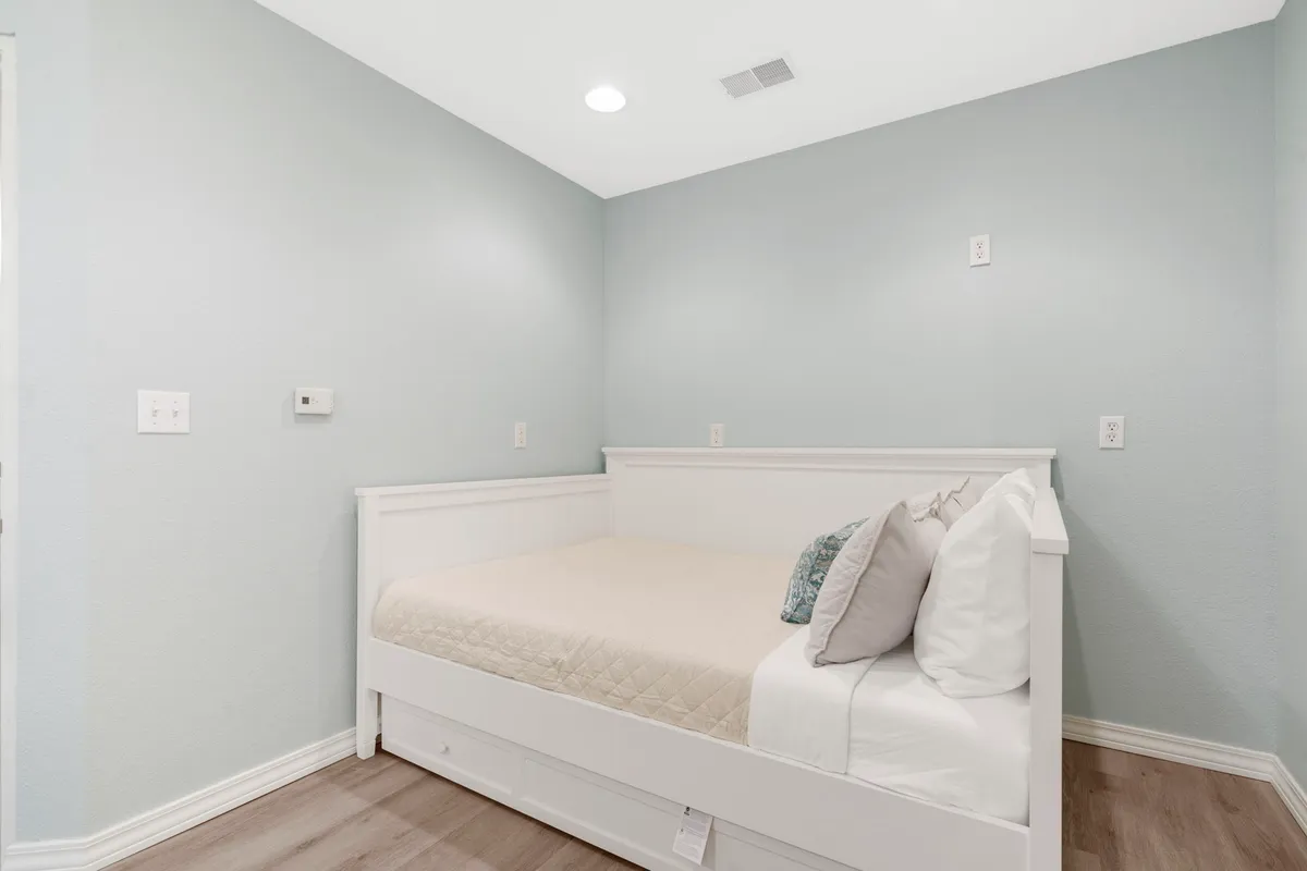 A serene interior bedroom scene featuring a large, inviting bed with plush pillows, soft wall color, and a tranquil atmosphere — the ideal space for rest and relaxation after a day of adventure.